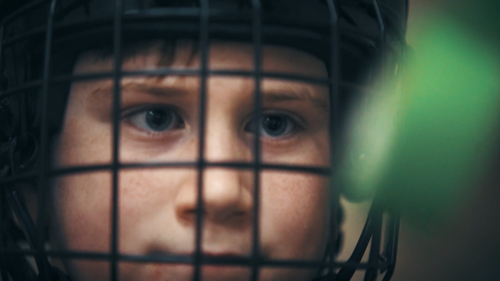 A young player's eyes seen through the helmet cage